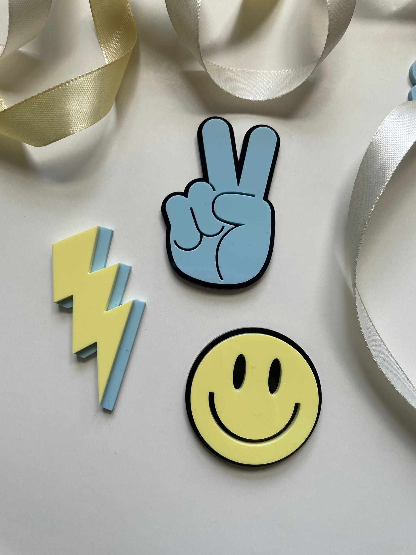 young wild and three acrylic cake topper set in blue yellow and black with lightning peace hand and smiley face charm